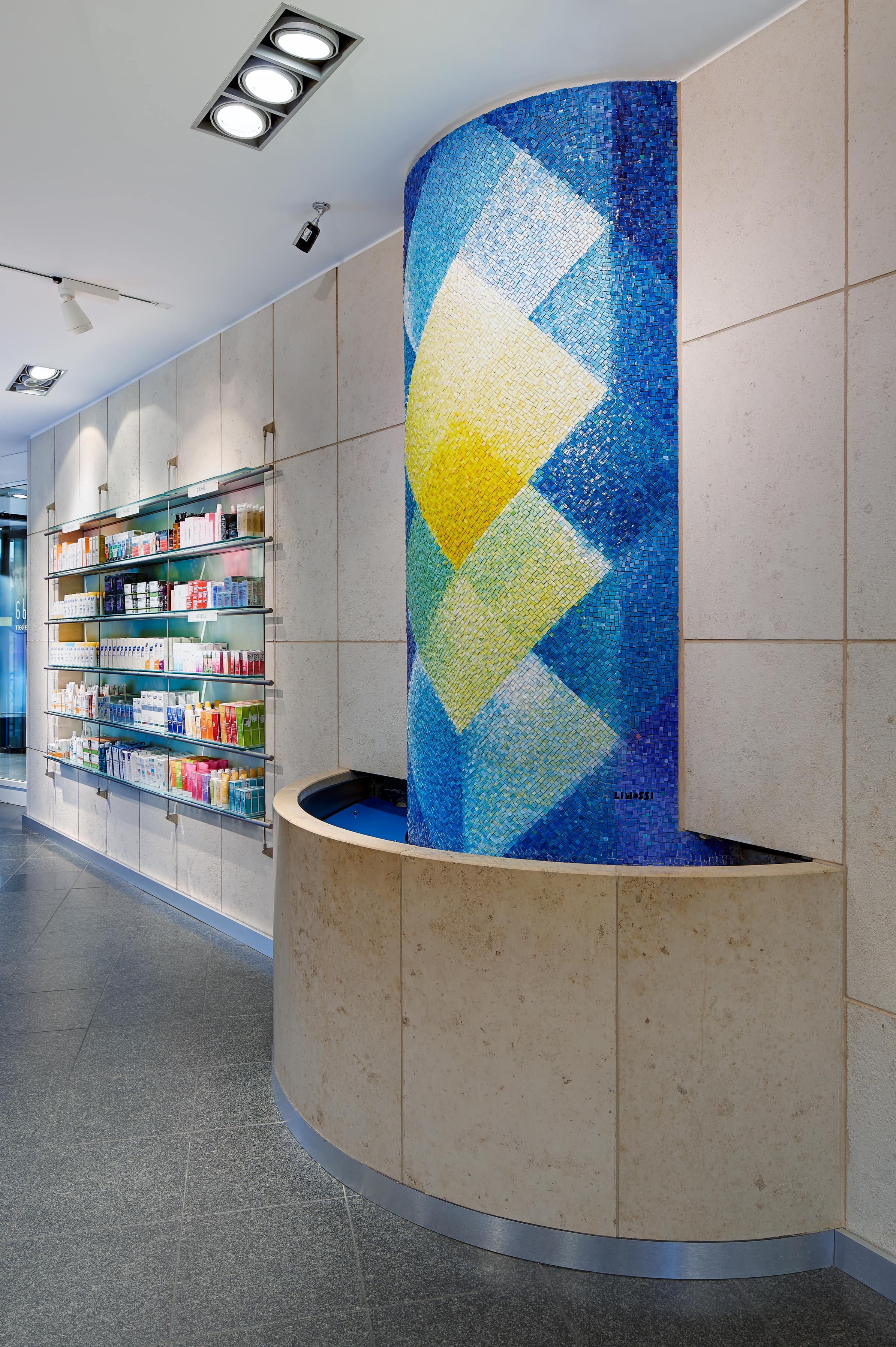 Detail of the semicircular wall fountain with the vivid blue-and-yellow mosaic by artist Lino Linossi