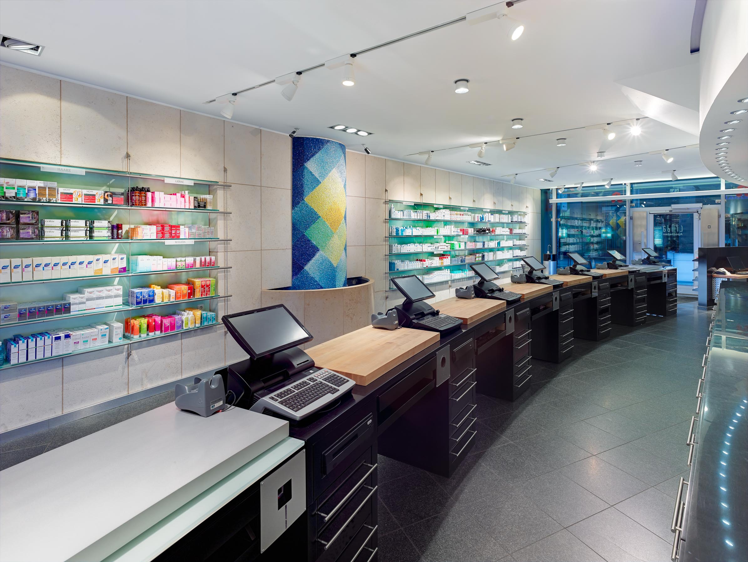 Working side of the sales counter with integrated checkout positions, wooden work surfaces and drawer units