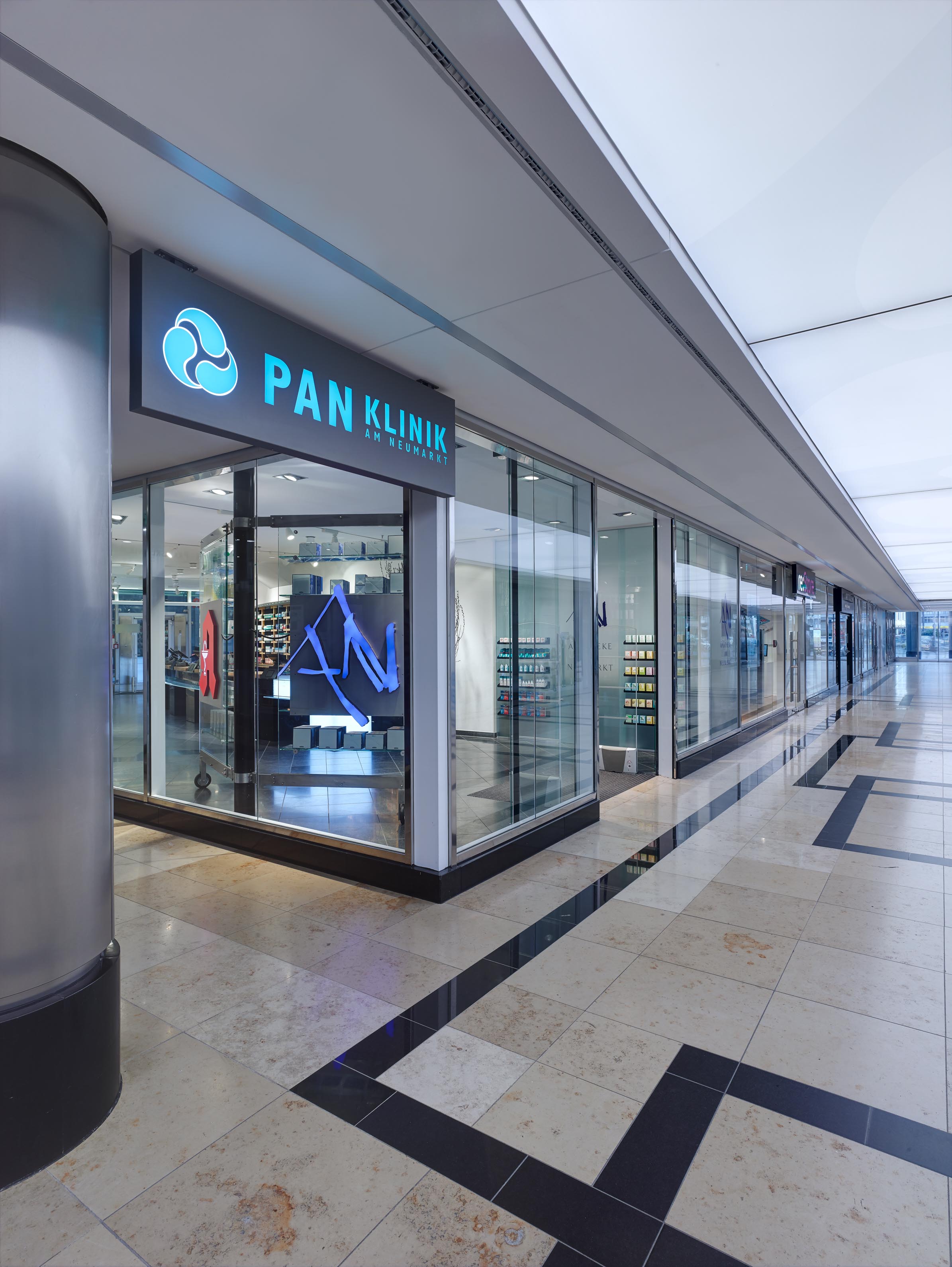 Corner view of the arcade façade beneath the illuminated PAN Clinic sign at Neumarkt