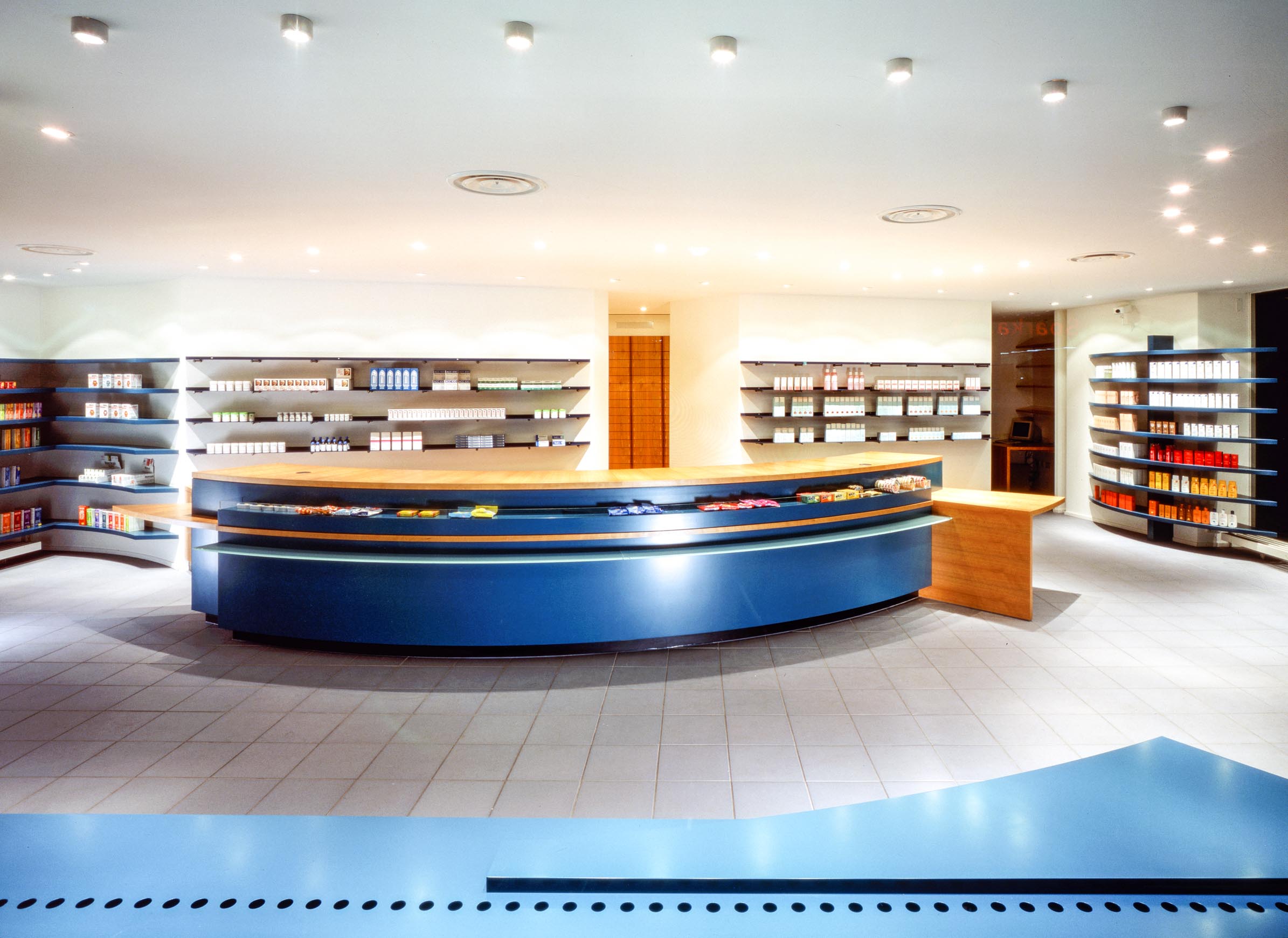 Overview of the Elephant Pharmacy dispensary in Gladbeck with a curved blue prescription counter and surrounding medicine display
