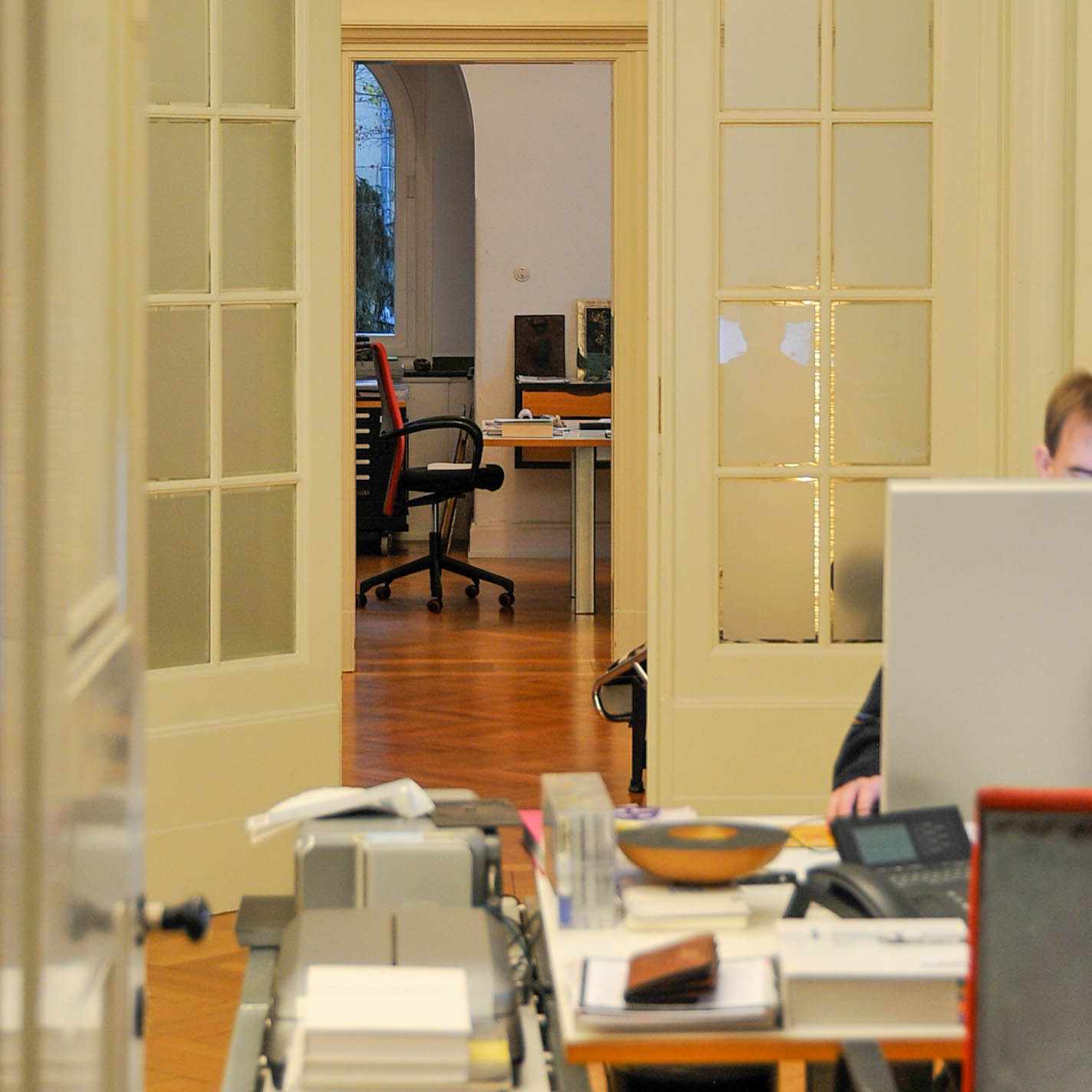 View through the open French doors of the architecture studio in Krefeld, revealing historic interiors, herringbone parquet flooring and workstations